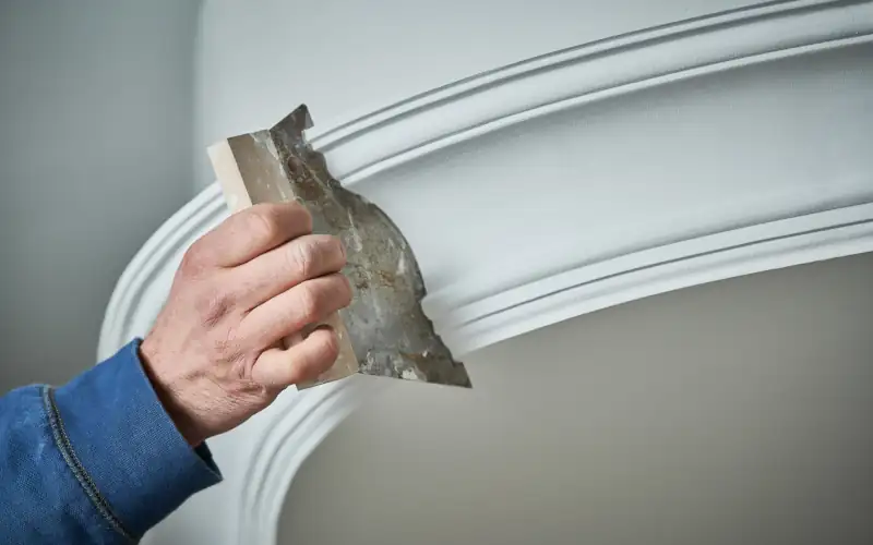 Ein Stukkateur zieht eine Stukkleiste mit Stukkschablone